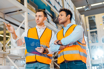 attentive multicultural warehouse workers in safety vests working in plumbing department / Photodune, Misc