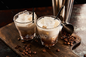 white russian cocktail in glasses with straws on wooden board with coffee grains / Photodune, Misc