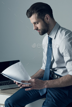 portrait of concentrated businessman sitting on table and reading documents / Photodune, Misc