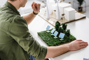 cropped view of architect sitting at table with solar panels and trees models in office / Photodune, Misc