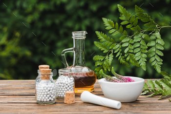selective focus of pestle near mortar with flowers, glass bottles with pills and jug with oil on / Photodune, Misc