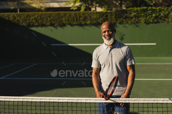 Portrait of smiling senior african american man holding tennis racket on tennis court / Photodune, Misc