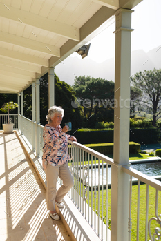 Senior caucasian woman standing on balcony holding mug and smiling / Photodune, Misc