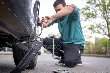 A male driver changes the wheel of a car on the road. / Photodune, Misc