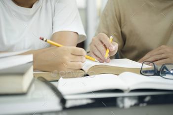 n and man studying for a test or an exam. Tutor books with friends. Young students campus helps friend catching up and learning.