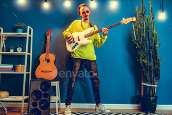 Cool guy with dreads practicing playing guitar at home / Photodune, Misc