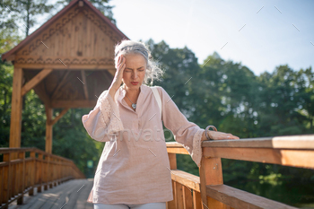 Woman suffering from headache while walking in the park / Photodune, Misc