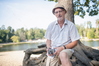 Man wearing checked shirt sitting near tree / Photodune, Misc