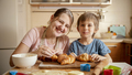 Smiling and laughing mother with little son eating freshly baked croissants on messy kitchen at home - PhotoDune Item for Sale
