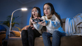 Happy laughing girls celebrating after victory in video game on console at night - PhotoDune Item for Sale