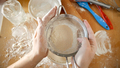 Top view of young woman shaking sieve for sifting flour while making dough - PhotoDune Item for Sale