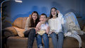 Smiling little boy with two teenage girls watching late night TV show and eating popcorn from big - PhotoDune Item for Sale