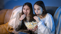 Happy smiling girls enjoying watching TV show and eating popcorn at night - PhotoDune Item for Sale