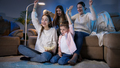 Happy cheerful family celebrating victory or football goal while watching TV at night - PhotoDune Item for Sale