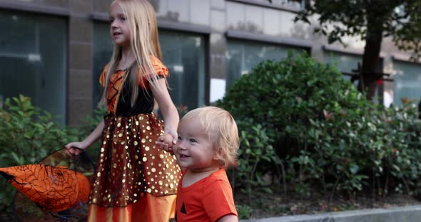 Cute Little Caucasian Kids with Blonde Hair Seven Years Old in Costume of Witch with Hat and Baby