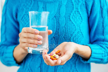 The person holds the medicine and a glass of water in his hands. / Photodune, Misc