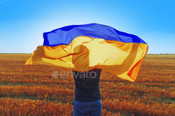 Man with a flag of Ukraine standing in field