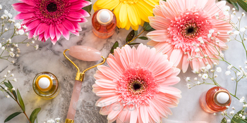 Pink quartz face roller gua sha and serum in bottle on marble table. Skin care concept with flowers / Photodune, Misc