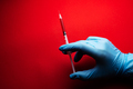Doctor holding medical syringe on red background - PhotoDune Item for Sale