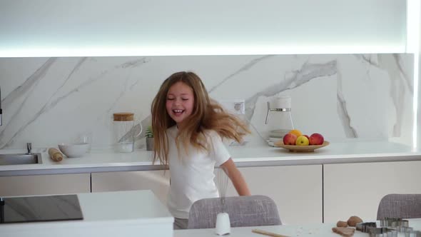 Happy Beautiful Little Girl Dancing in Modern Kitchen Having Fun Doing Funny Dance Moves