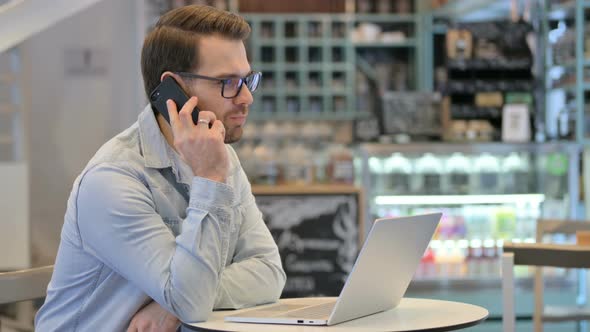 Man with Laptop Talking on Phone