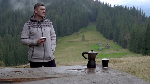 A Man Drinks Coffee and Looks at the Beautiful Landscape. Coffee Maker and Mug on the Table