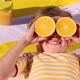 Happy child holding halves of orange fruit like a sunglasses. Slow motion - VideoHive Item for Sale