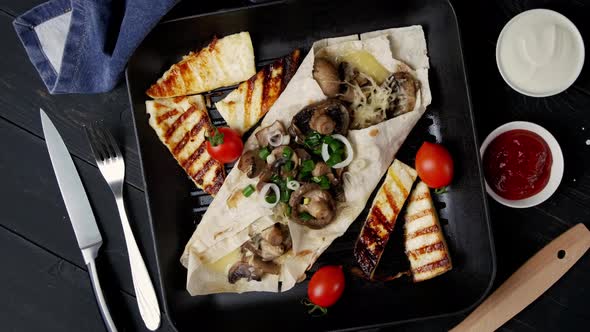 Vegetarian Pita Bread with Mushrooms and Cheese Rotates on a Wooden Table in a Square Skillet Grill