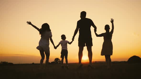 Happy Family Parents and Childrens Silhouettes Playing on Park