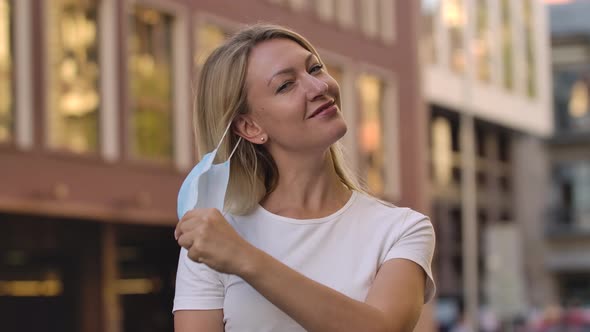 Portrait of Pretty Young Woman Removes a Protective Medical Mask From the Face Rejoices and Smiles