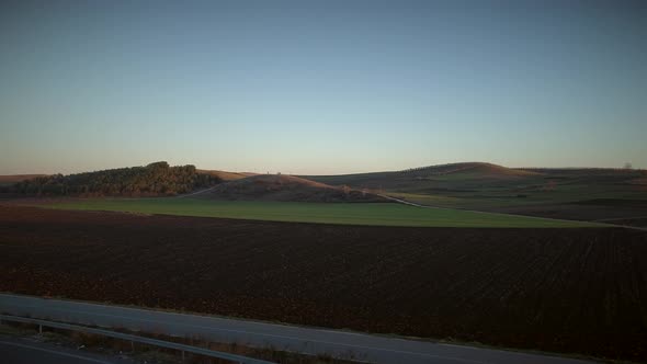 Aerial view of beautiful hills with lots of grass at sunset.