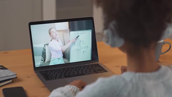 African Girl Sits at a Desk and Study Online Using a Laptop a Schoolgirl Learns in a Remote Lesson