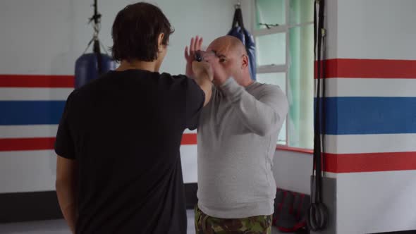 Caucasian man learning self defense from trainer in gym