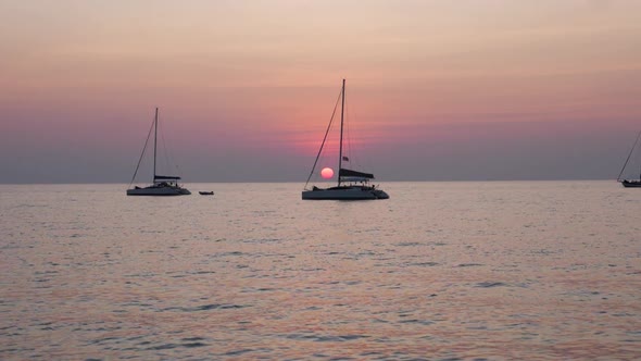 Sailboats in front of beautiful sunset - ultra slow motion