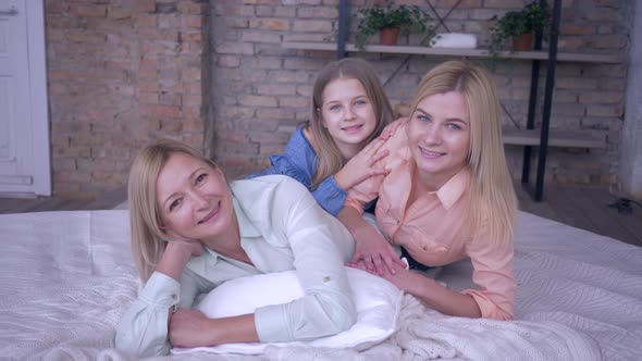 Family Relax at Home, Laughing Women with Funny Girls Daughters Lying on Bed While Leisure Time in