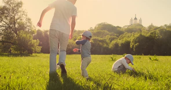 Father with Two Sons Playing Football in the Meadow