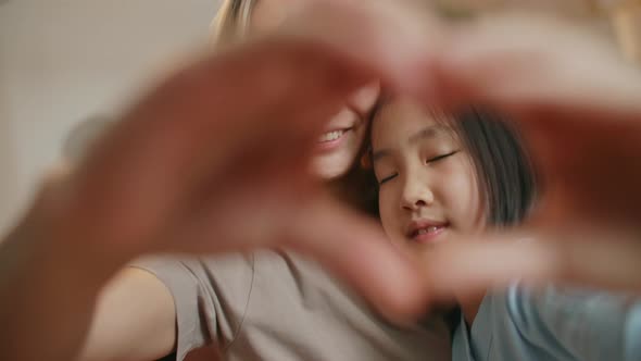 Beautiful Asian Happy Mother and Little Cute Daughter Faces Seen Through Joined Fingers Making Heart