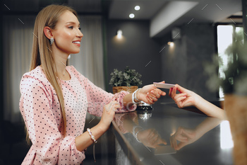 Young woman hotel guest receiving key card from receptionist / Photodune, Misc