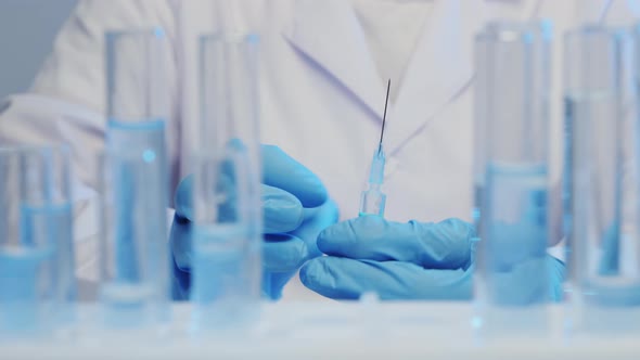 Doctor Hold a Syringe with a Vaccine in the Foreground a Test Tube