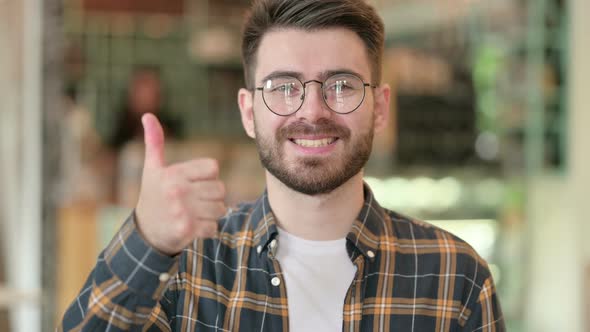 Portrait of Positive Young Man Doing Thumbs Up