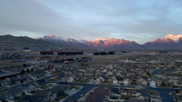 Idyllic Community below snow-capped mountains at sunset - sliding aerial hyper lapse