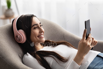 Woman enjoys spare time, mobile audio application, favorite music and study online / Photodune, Misc