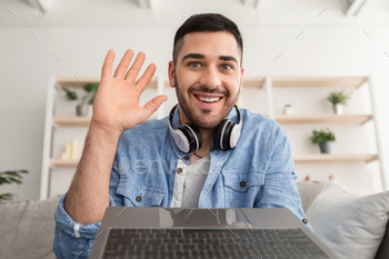 Cheerful jew man having video call using laptop and waving / Photodune, Misc