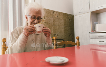 Old woman drinking a coffee in the kitchen / Photodune, Misc