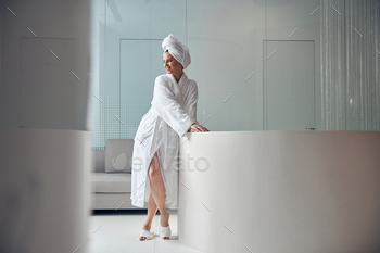 Svelte lady standing cross-legged in a foyer