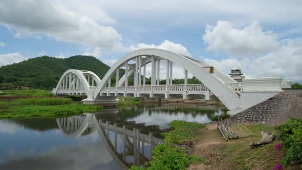 Time lapse of Tha Chomphu White Bridge, Lamphun, Thailand with lake or river, forest trees