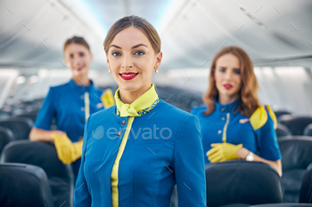 s blue uniform standing in the salon of first class of commercial airplane