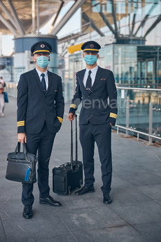 Male airline workers in medical masks standing on the street / Photodune, Misc