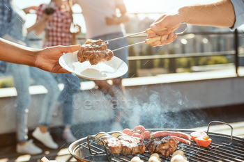 Cropped photo of male hand putting hot barbecued meat on the plate / Photodune, Misc