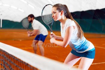 Pair of tennis players, man and woman waiting for service at indoor court / Photodune, Misc